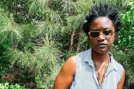 Black woman in sunglasses in front of trees